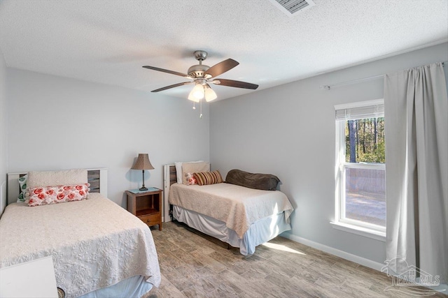 bedroom with ceiling fan, hardwood / wood-style floors, and a textured ceiling