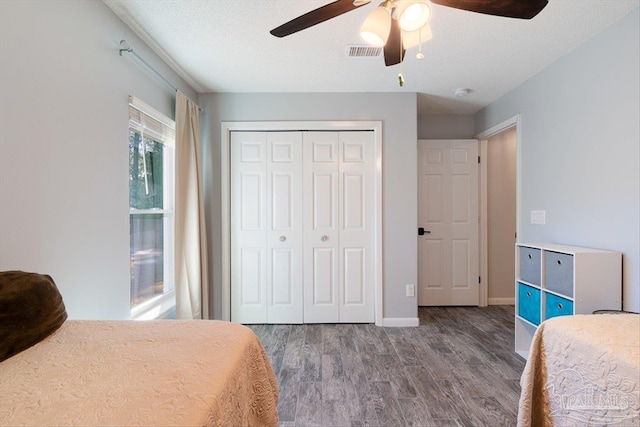 bedroom with hardwood / wood-style flooring, a textured ceiling, a closet, and ceiling fan