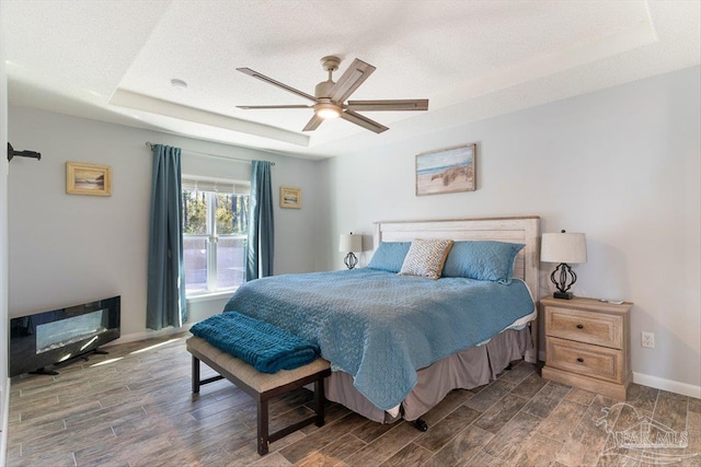 bedroom featuring a raised ceiling, a textured ceiling, and ceiling fan