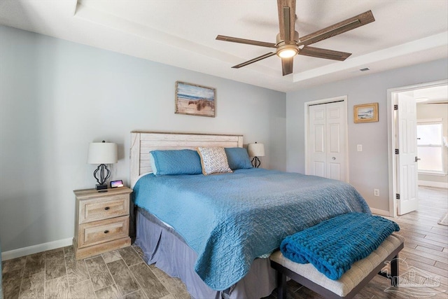 bedroom with ceiling fan, a tray ceiling, and a closet