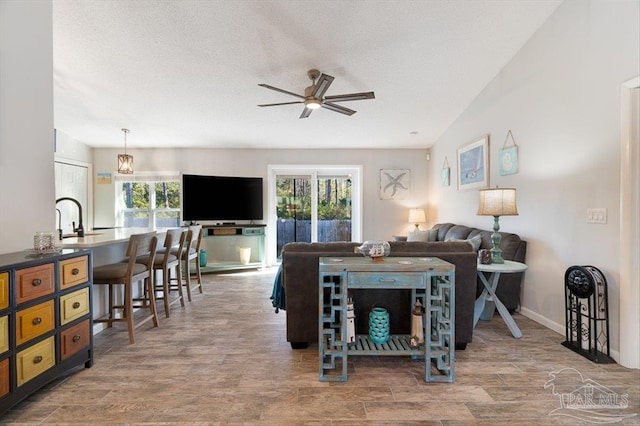 living room featuring sink, a textured ceiling, wood-type flooring, and ceiling fan