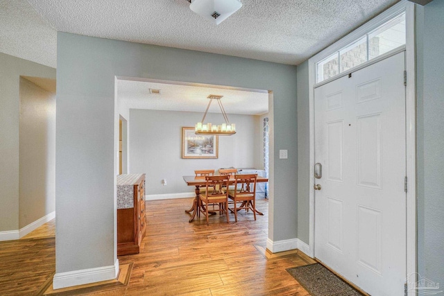 entryway with a notable chandelier, a textured ceiling, and light hardwood / wood-style floors