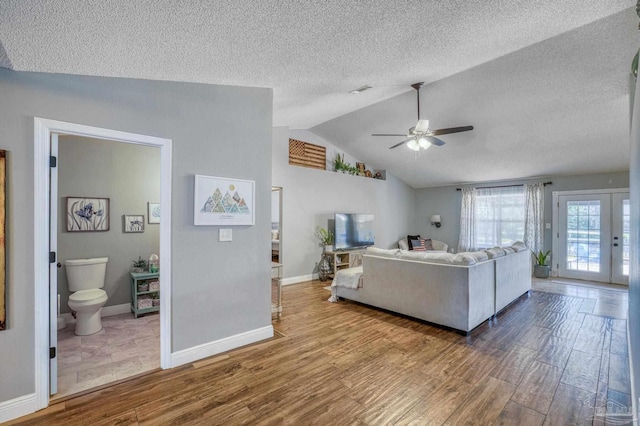 living room with ceiling fan, a textured ceiling, and vaulted ceiling