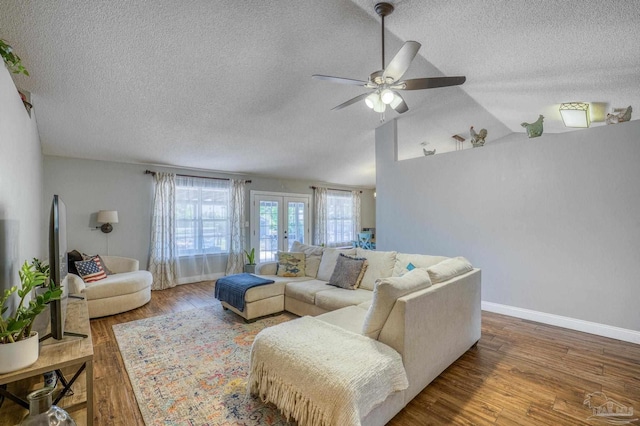 living room featuring ceiling fan, vaulted ceiling, hardwood / wood-style flooring, a textured ceiling, and french doors