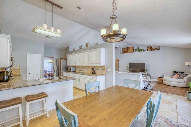 dining area with a textured ceiling, lofted ceiling, and sink