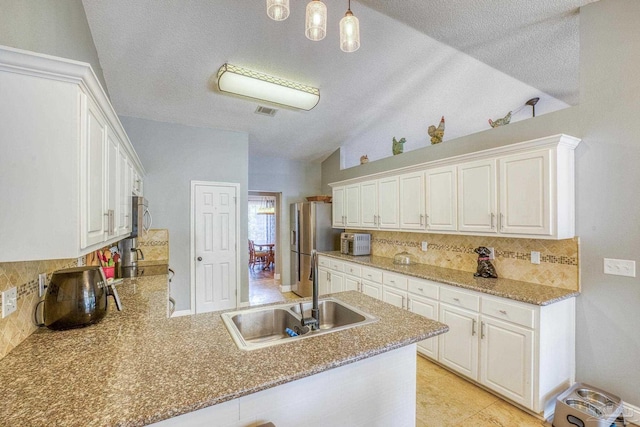 kitchen featuring white cabinetry, stainless steel appliances, sink, kitchen peninsula, and vaulted ceiling