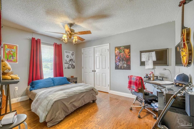 bedroom with ceiling fan, a textured ceiling, light hardwood / wood-style flooring, and a closet