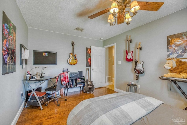 bedroom with a textured ceiling, ceiling fan, and wood-type flooring