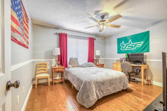 bedroom with ceiling fan, hardwood / wood-style floors, and a textured ceiling