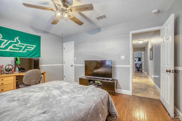 bedroom with a textured ceiling, ceiling fan, and hardwood / wood-style flooring