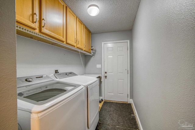 clothes washing area featuring washing machine and dryer, cabinets, and a textured ceiling