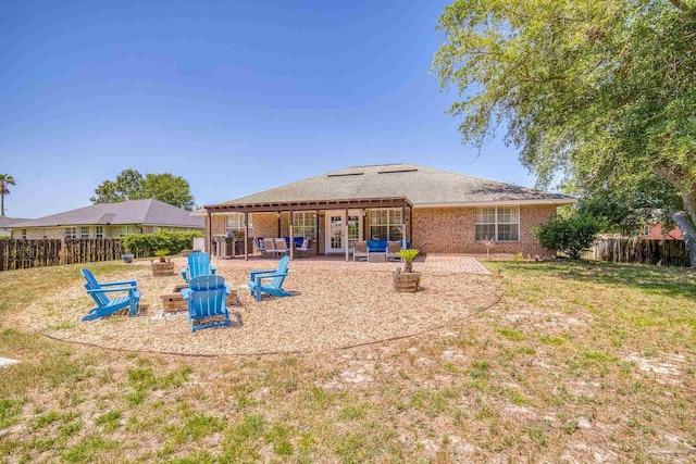 back of property with a lawn, a patio area, and a fire pit