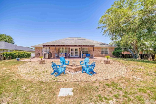 back of property with french doors, a yard, and a fire pit