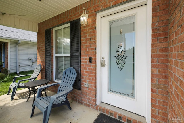 property entrance featuring brick siding and covered porch