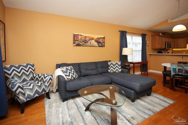 living area with light wood finished floors, baseboards, and vaulted ceiling