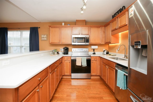 kitchen featuring kitchen peninsula, appliances with stainless steel finishes, light hardwood / wood-style flooring, and sink