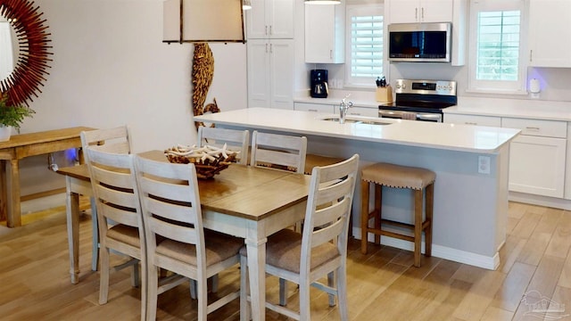 kitchen with a healthy amount of sunlight, light wood-style floors, appliances with stainless steel finishes, and a sink