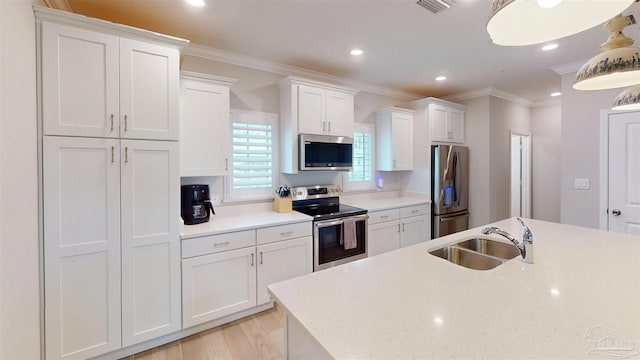 kitchen featuring ornamental molding, a sink, light countertops, white cabinets, and appliances with stainless steel finishes