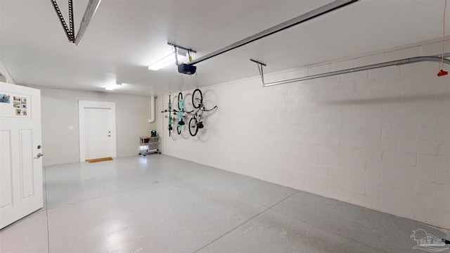 garage featuring concrete block wall and a garage door opener