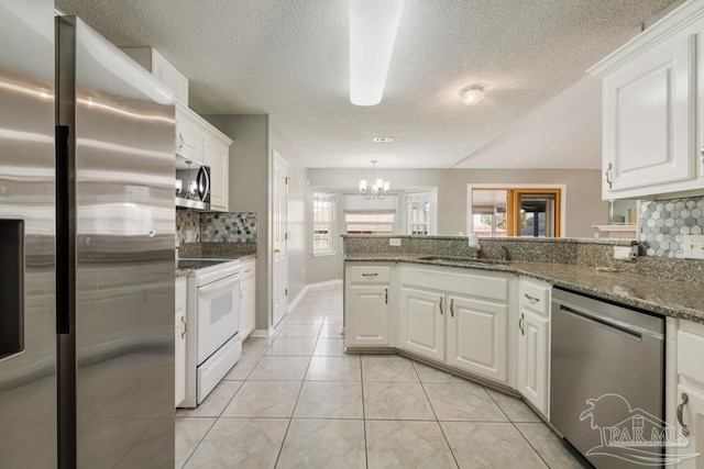 kitchen featuring sink, dark stone counters, white cabinets, and appliances with stainless steel finishes