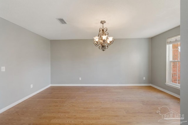 unfurnished room featuring a notable chandelier and light hardwood / wood-style floors