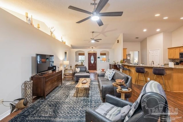 living room featuring dark hardwood / wood-style flooring, vaulted ceiling, and ceiling fan