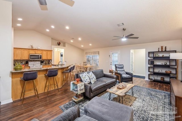 living room featuring ceiling fan, lofted ceiling, and dark hardwood / wood-style flooring