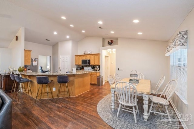 dining area with lofted ceiling, dark hardwood / wood-style floors, and sink