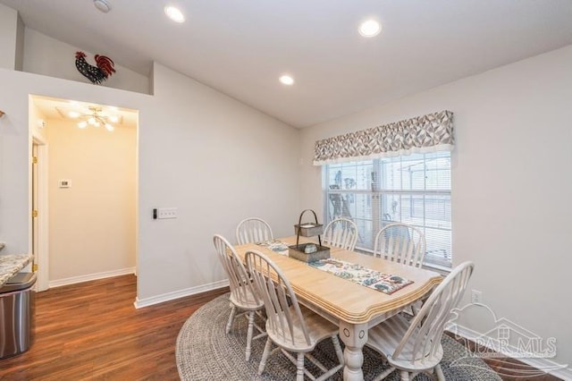 dining room with lofted ceiling, dark hardwood / wood-style floors, and a chandelier