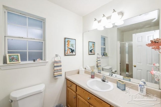 bathroom with walk in shower, vanity, and toilet