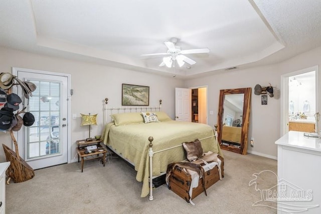 bedroom featuring ceiling fan, light colored carpet, a tray ceiling, and access to outside