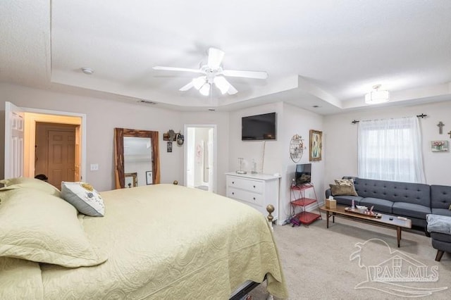 carpeted bedroom featuring ceiling fan and a tray ceiling