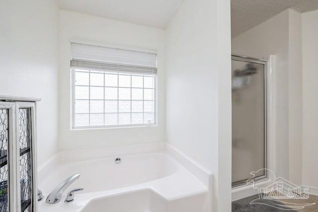 bathroom with shower with separate bathtub and a textured ceiling