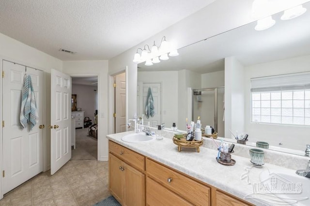 bathroom featuring vanity, a shower with door, and a textured ceiling