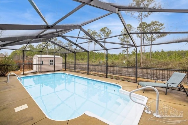 view of pool with a patio, glass enclosure, and a storage shed