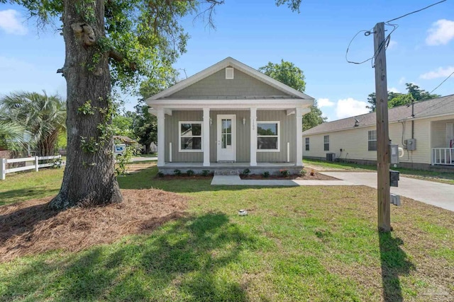 view of front of house with central AC unit, covered porch, fence, board and batten siding, and a front yard