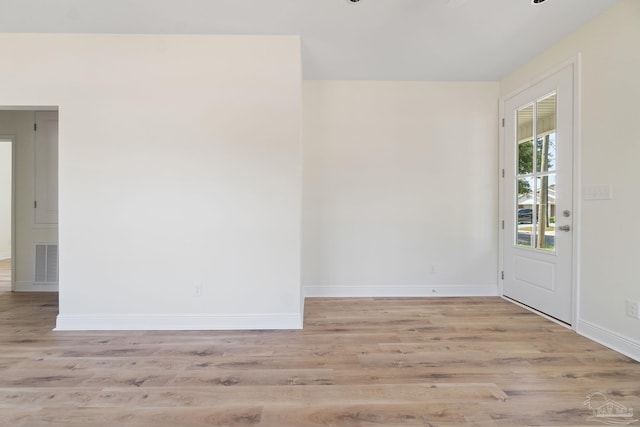 empty room featuring visible vents, baseboards, and wood finished floors