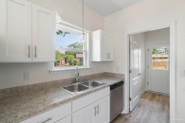 kitchen with stainless steel dishwasher, plenty of natural light, white cabinets, and a sink