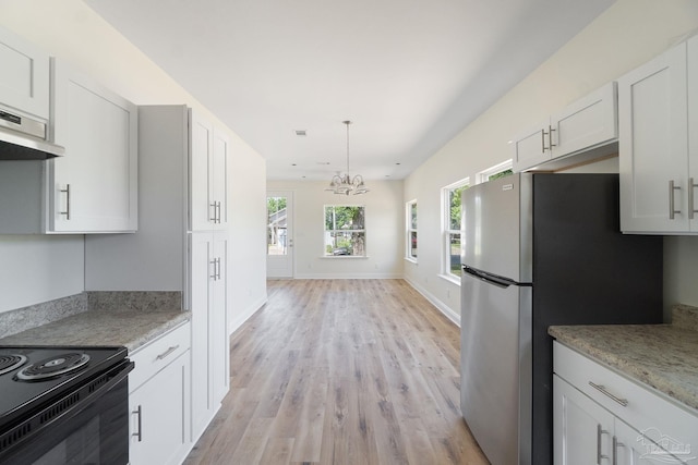 kitchen with light wood finished floors, baseboards, decorative light fixtures, freestanding refrigerator, and white cabinetry