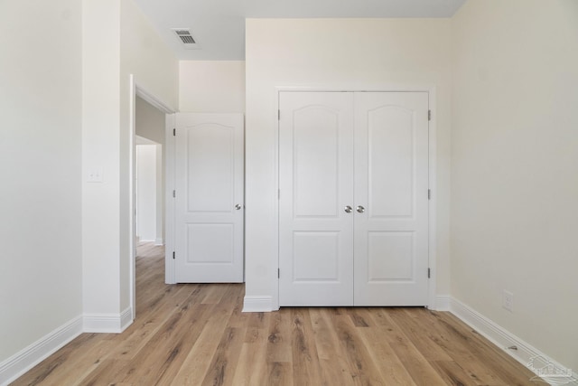 unfurnished bedroom with baseboards, light wood-style flooring, visible vents, and a closet