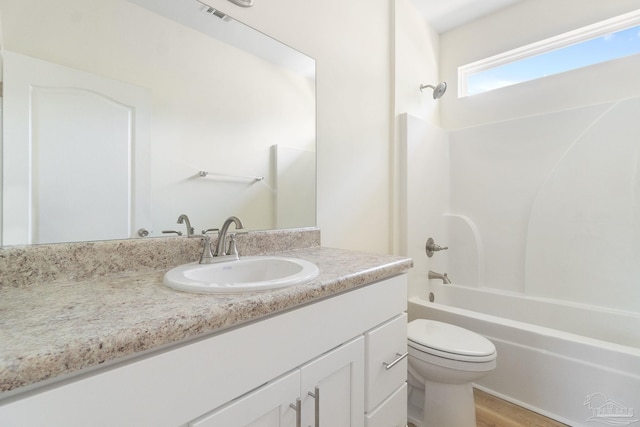 bathroom with visible vents, toilet, wood finished floors, vanity, and shower / bathing tub combination