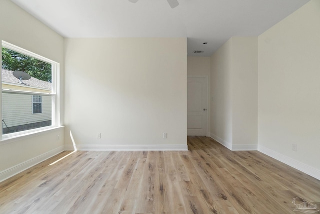 empty room featuring a ceiling fan, light wood-type flooring, visible vents, and baseboards