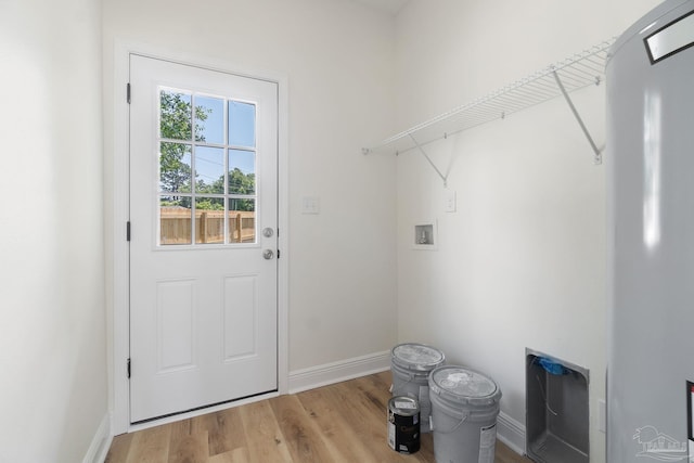 laundry area featuring laundry area, baseboards, wood finished floors, hookup for a washing machine, and water heater