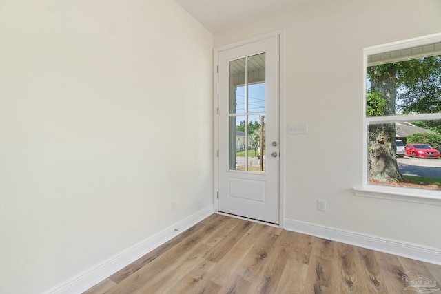 doorway to outside with light wood finished floors and baseboards