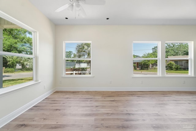 unfurnished room with light wood-type flooring, a healthy amount of sunlight, ceiling fan, and baseboards