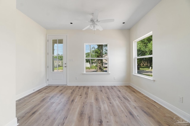 unfurnished room featuring light wood-style floors, a ceiling fan, baseboards, and a wealth of natural light