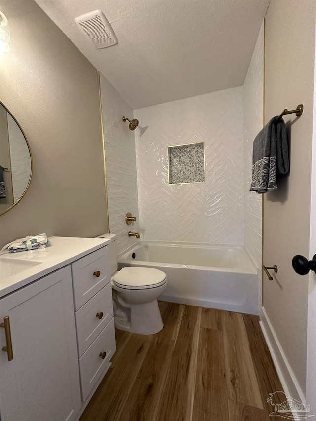 full bathroom featuring toilet, tiled shower / bath, a textured ceiling, vanity, and hardwood / wood-style floors