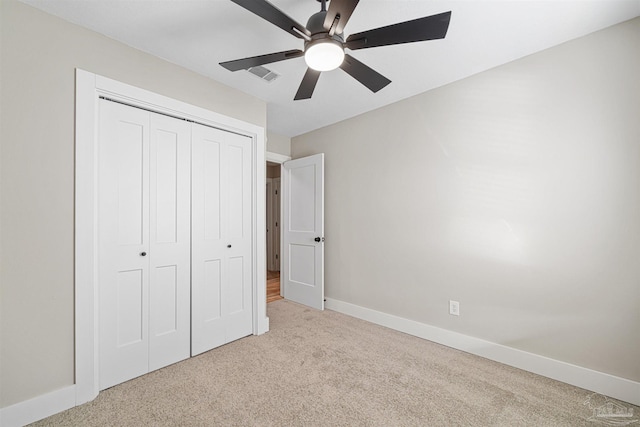 unfurnished bedroom featuring ceiling fan, a closet, and light carpet