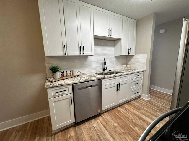 kitchen with light stone counters, stainless steel dishwasher, and white cabinets