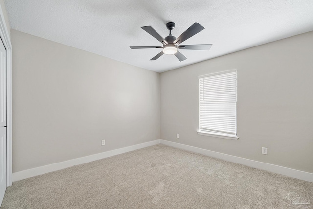 carpeted empty room featuring ceiling fan and a textured ceiling